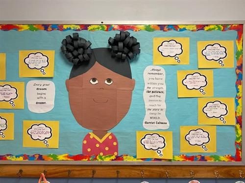 Colorful bulletin board with a construction-paper-made picture of Harriet Tubman surrounded by quotes of student dreams.